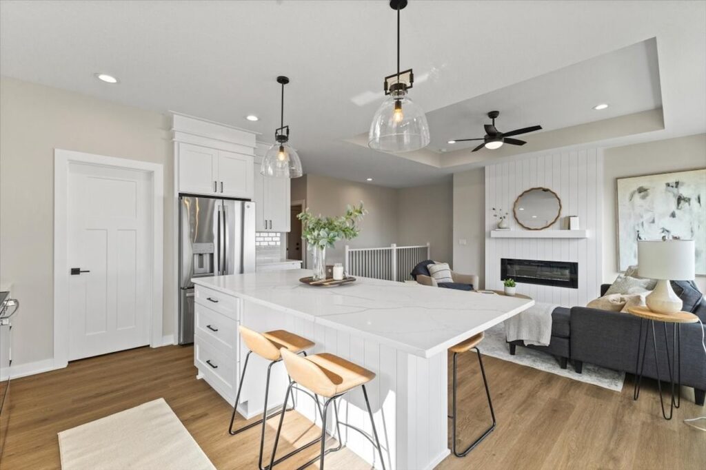 Bright kitchen with white cabinetry and a marble island, part of new Gladiator Homes available in Norwalk, IA.