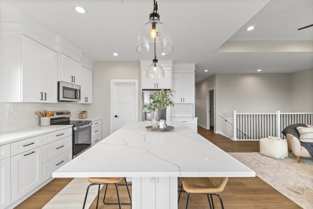 Modern kitchen featuring white cabinets and a marble island, showcasing new Gladiator Homes for sale in Norwalk, IA.