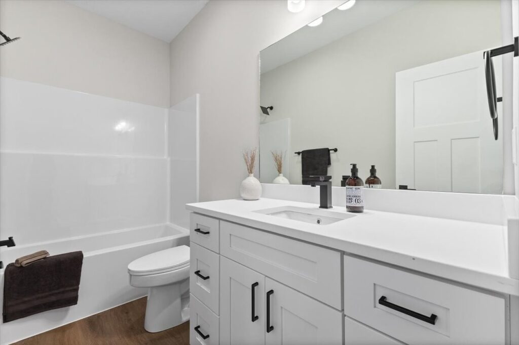 Modern bathroom with white cabinets and a large mirror, highlighting new Gladiator homes for sale at 304 S Valley View Dr.