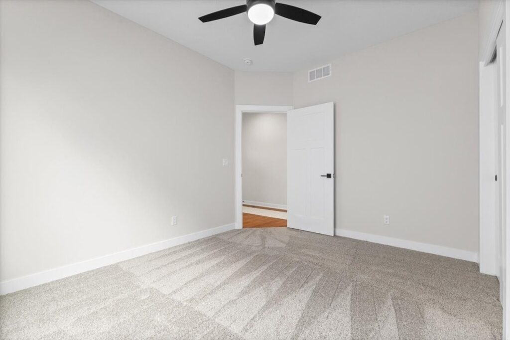 Empty room featuring a ceiling fan and a window, showcasing new Gladiator homes for sale in Norwalk, IA.