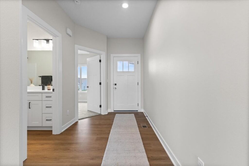 Hallway featuring white cabinets and hardwood floors, showcasing new Gladiator Homes for sale in Norwalk, IA.