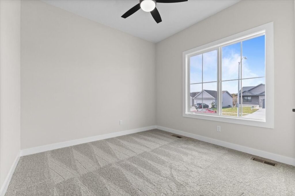 Empty room featuring a ceiling fan and a window, showcasing new Gladiator homes for sale in Norwalk, IA.