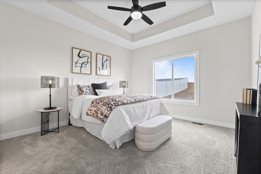 Cozy bedroom with a white bed and ceiling fan, part of new Gladiator homes available at 304 S Valley View Dr, Norwalk, IA.