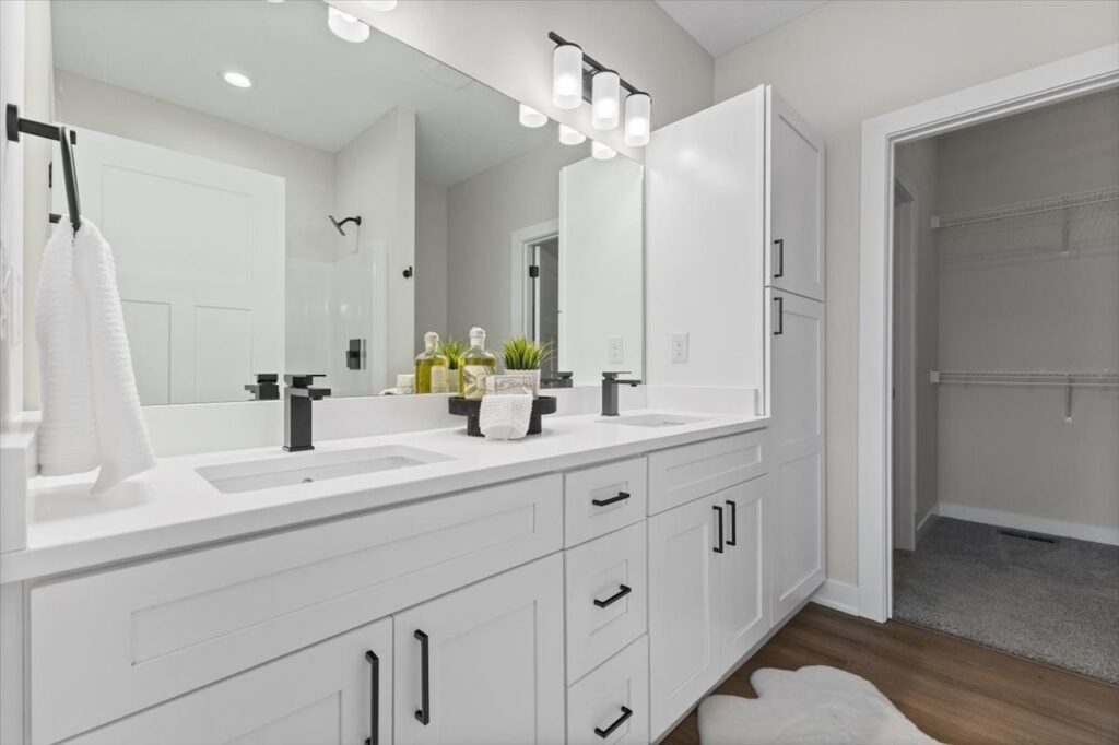 Clean bathroom featuring white cabinets and a large mirror, showcasing new Gladiator homes for sale in Norwalk, IA.
