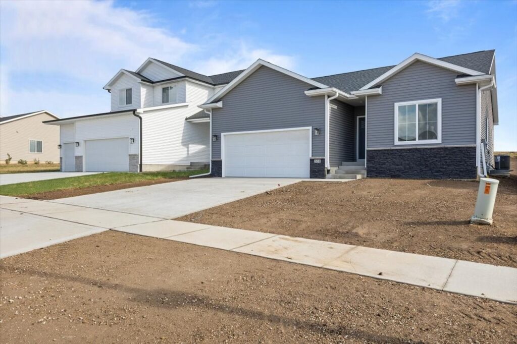A residential property with two garages and a driveway, highlighting new Gladiator Homes available at 304 S Valley View Dr, Norwalk, IA.