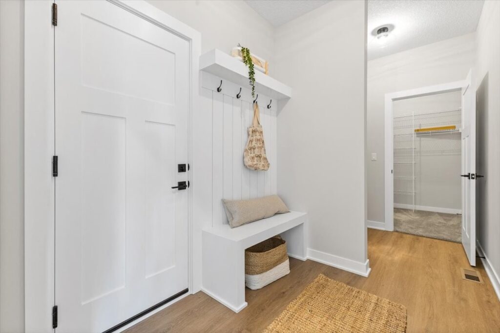 Hallway featuring a white door and bench, highlighting new Gladiator Homes available at 304 S Valley View Dr, Norwalk, IA.