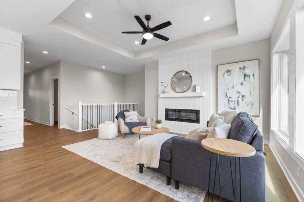 Stylish living room with a fireplace, couches, and a ceiling fan, part of new Gladiator Homes for sale in Norwalk, IA.