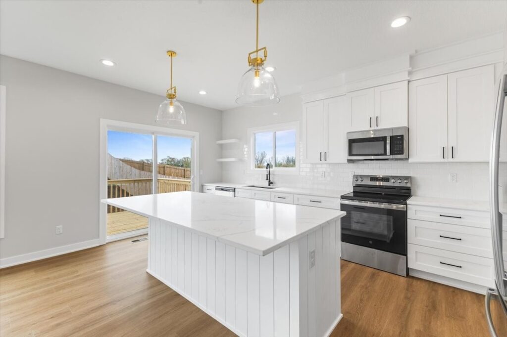 Modern kitchen featuring white cabinets and a marble island, showcasing new Gladiator Homes for sale in Norwalk, IA.