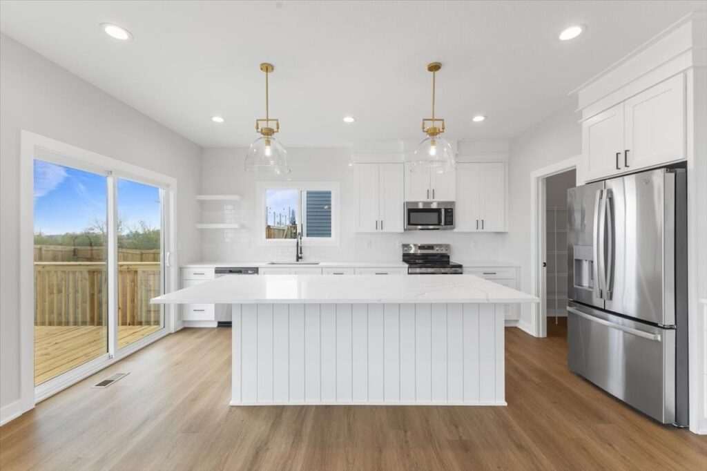 Modern kitchen featuring white cabinets and a marble island, showcasing new Gladiator Homes for sale in Norwalk, IA.