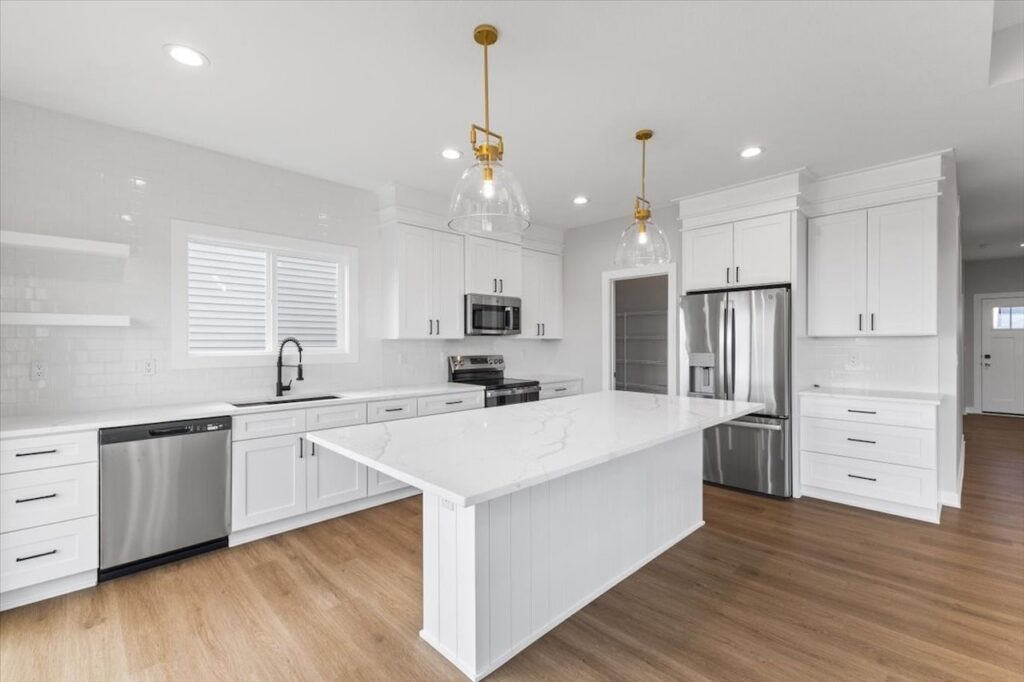 Modern kitchen featuring white cabinets and a marble island, showcasing new Gladiator Homes for sale in Norwalk, IA.