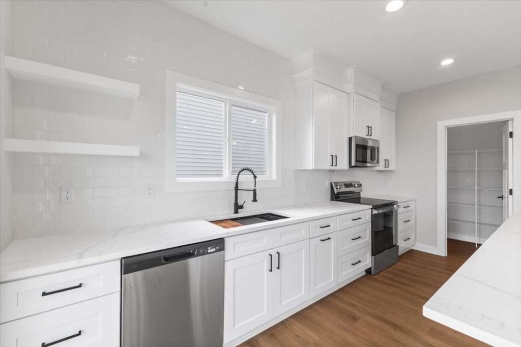 Elegant kitchen with white cabinets and a marble island, highlighting new Gladiator Homes for sale at 304 S Valley View Dr.
