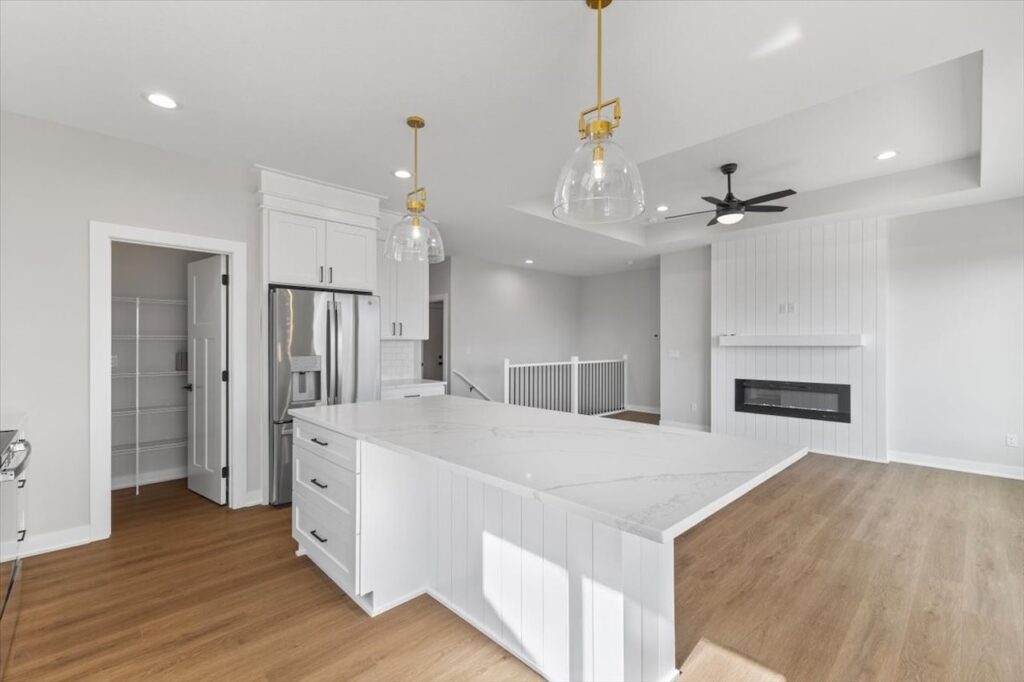Modern kitchen featuring white cabinets and a marble island, showcasing new Gladiator Homes for sale in Norwalk, IA.