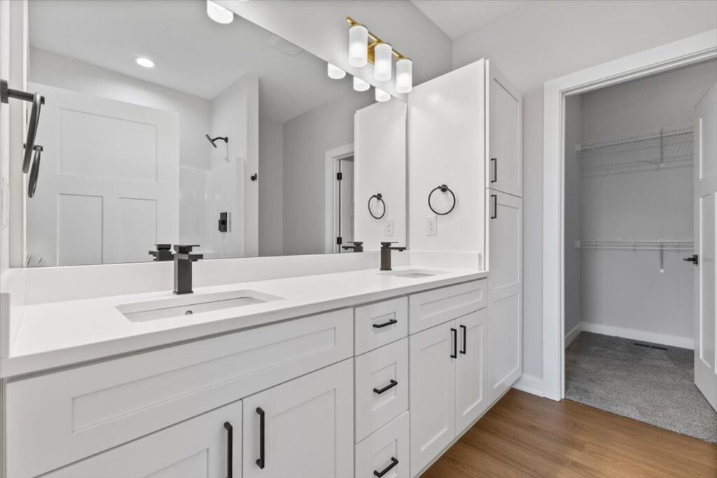 Modern white bathroom with a sink, toilet, and shower, part of new homes available at 308 S Valley View Dr, Norwalk, IA.
