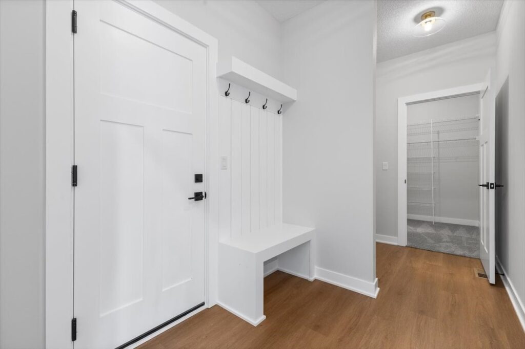 Hallway featuring a white door and bench, highlighting new Gladiator Homes available at 308 S Valley View Dr, Norwalk, IA.