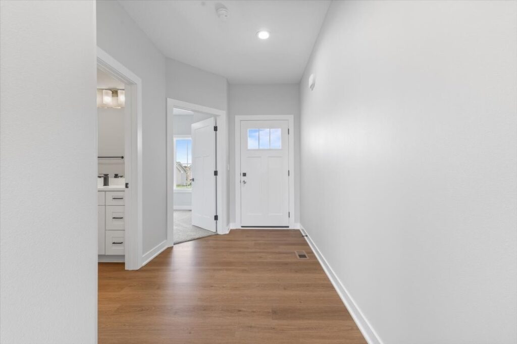 Bright hallway featuring white walls and hardwood floors, part of new Gladiator Homes for sale at 308 S Valley View Dr, Norwalk, IA.