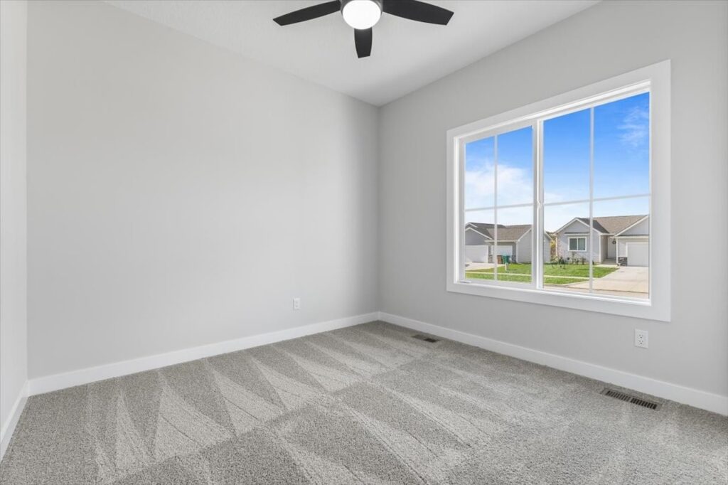 Empty room featuring a ceiling fan and a window, showcasing new Gladiator homes for sale in Norwalk, IA.