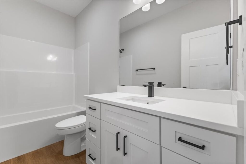 Clean bathroom featuring white cabinets and a large mirror, showcasing new Gladiator homes for sale in Norwalk, IA.