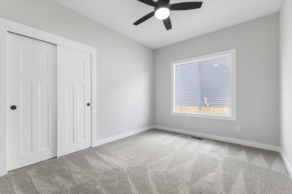 Empty room featuring a ceiling fan and a window, showcasing new Gladiator homes for sale in Norwalk, IA.
