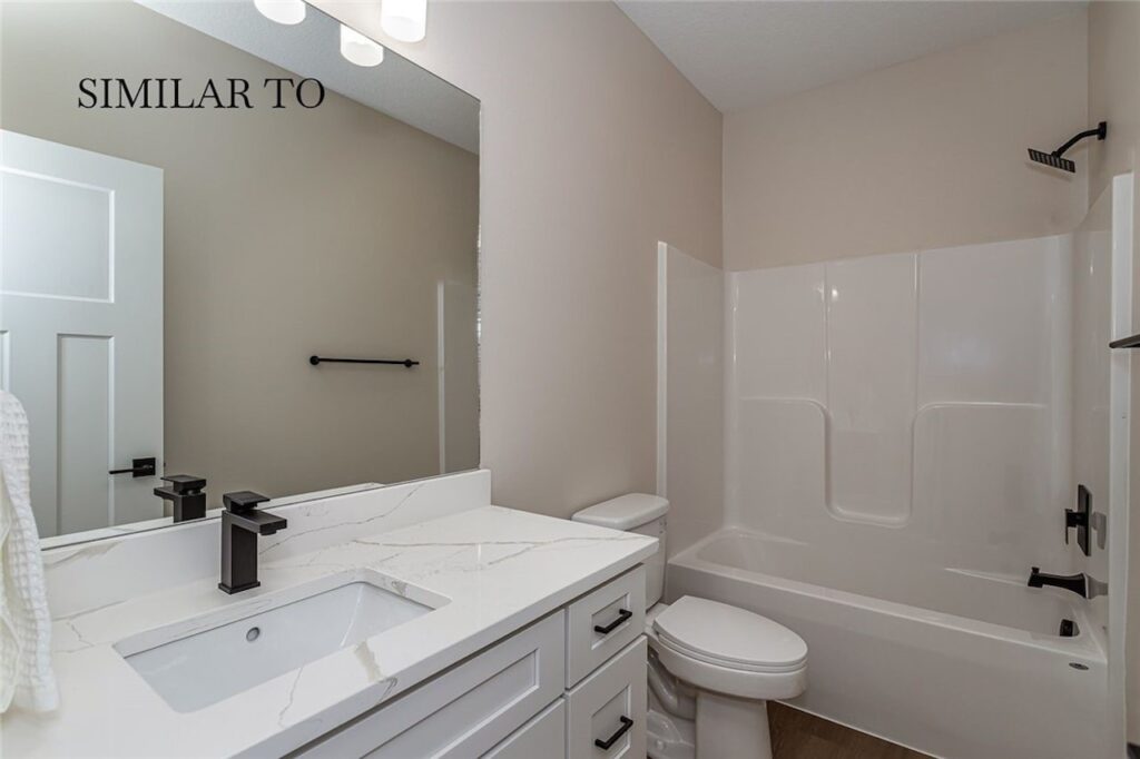 Modern bathroom with white fixtures and a sink, showcasing new homes available from Gladiator Homes in Norwalk, IA.