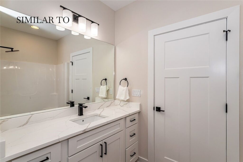 Elegant bathroom with white cabinets and a mirror, highlighting a property available for sale at 308 S Valley View Dr, Norwalk, IA.