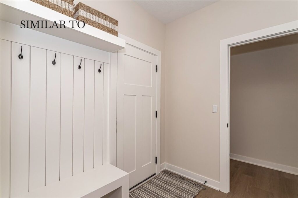 Clean white entryway with a bench and coat rack, promoting Gladiator Homes for sale at 308 S Valley View Dr, Norwalk, IA