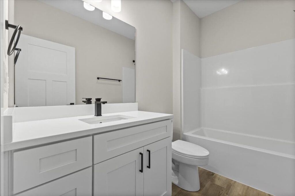 Modern bathroom showcasing white cabinets and a large mirror, within the Gladiator home for sale at 4517 NW 17th St, Ankeny, IA.