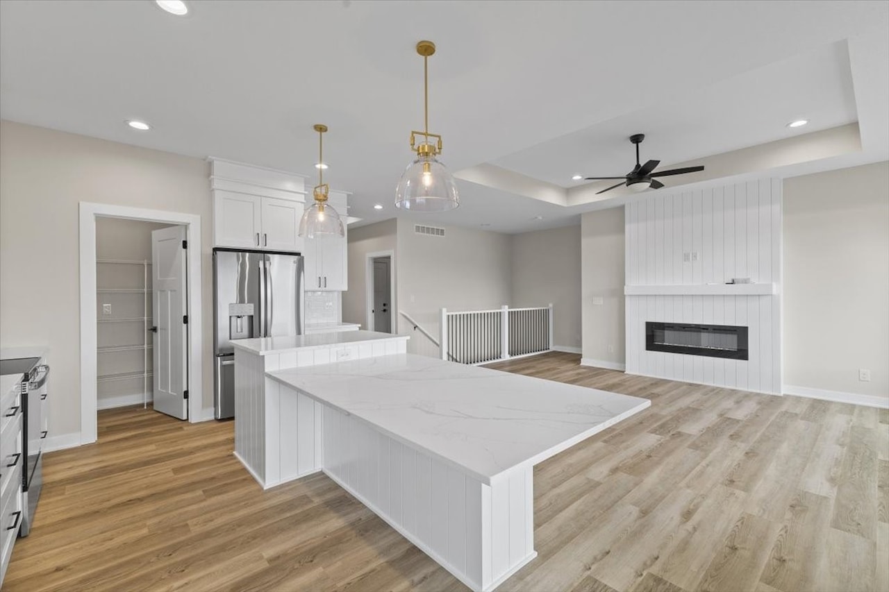 Elegant kitchen with white cabinetry and a marble island, located in the Gladiator home for sale in Ankeny, IA.