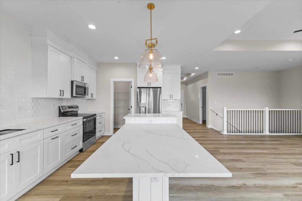 Modern kitchen featuring white cabinets and a marble island, part of the Gladiator home for sale in Ankeny, IA.