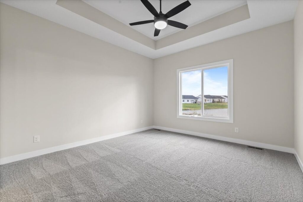 Spacious empty room with a ceiling fan and window, available in the New Gladiator home for sale at 4517 NW 17th St, Ankeny, IA.