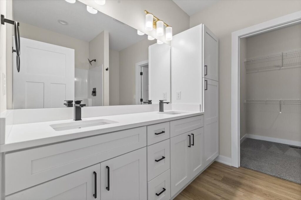 Modern bathroom showcasing white cabinets and a large mirror, within the Gladiator home for sale at 4517 NW 17th St, Ankeny, IA.