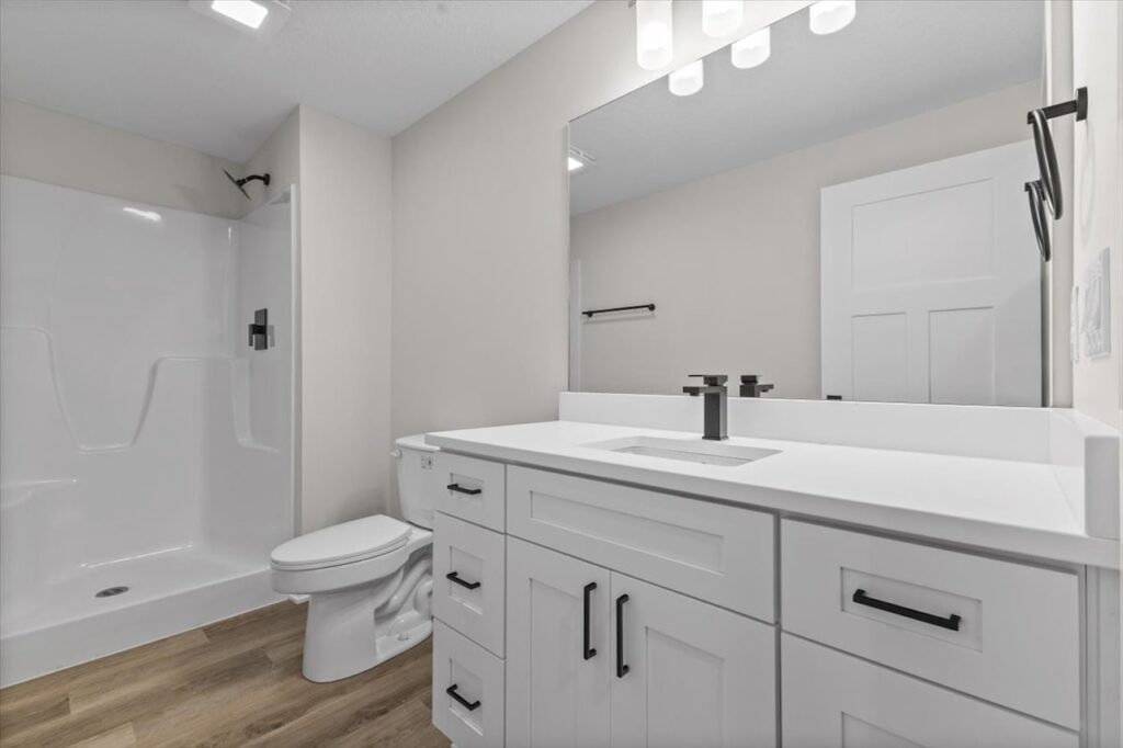 Bright bathroom with white cabinetry and a spacious mirror, located in the Gladiator home for sale at 4517 NW 17th St, Ankeny, IA.