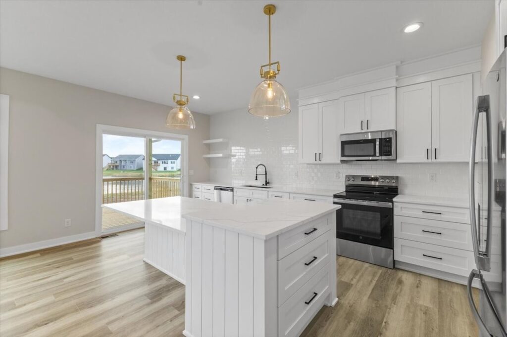 Modern kitchen with white cabinets and wood floors, part of the Gladiator home for sale at 4517 NW 17th St, Ankeny, IA.