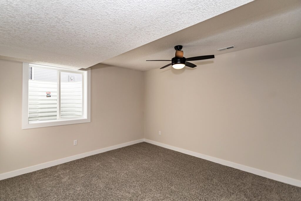 Interior view of a room with a ceiling fan and carpet, showcasing Gladiator Homes at 5825 Westfield Dr, Ames, IA.