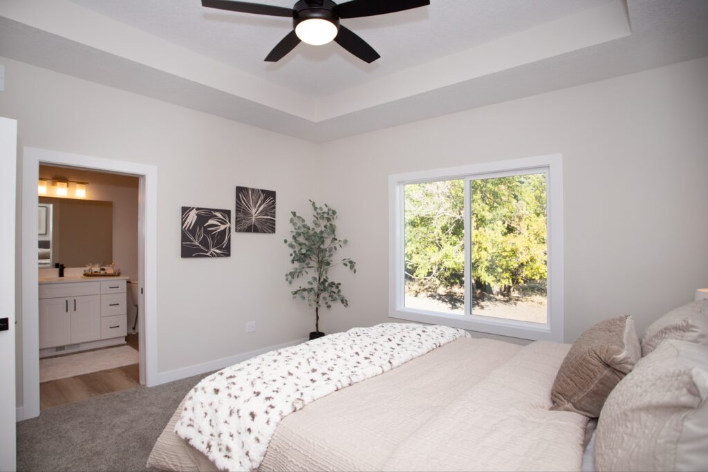 A cozy bedroom featuring a ceiling fan and a bed, showcasing Gladiator Homes for sale at 5825 Westfield Dr, Ames, IA.