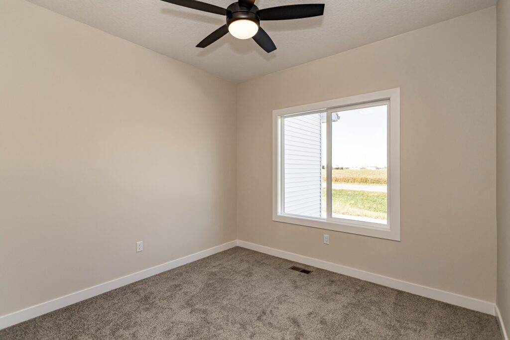 Interior view of a room with a ceiling fan and carpet, showcasing Gladiator Homes at 5825 Westfield Dr, Ames, IA.