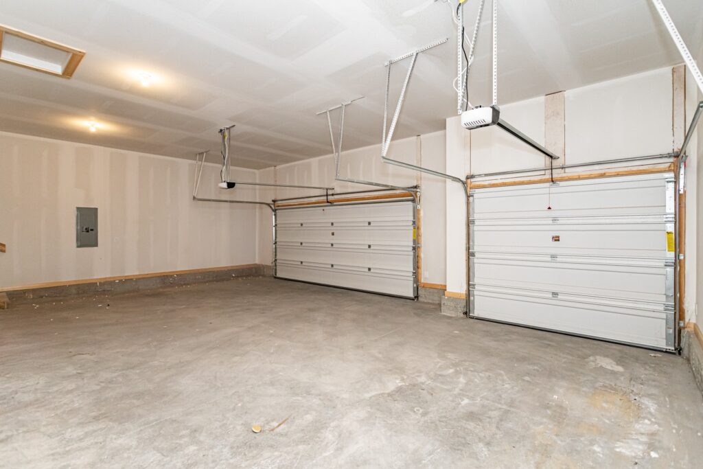 Spacious empty garage with two overhead doors and a ceiling fan, available at Gladiator Homes, 5825 Westfield Dr, Ames, IA.