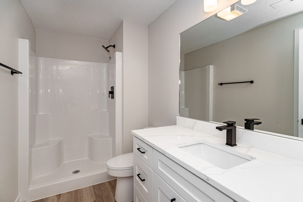 Elegant bathroom with white cabinets and a shower stall, available in Gladiator Homes at 5825 Westfield Dr, Ames, IA.
