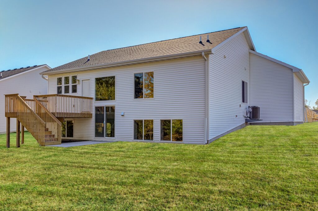 Exterior view of a spacious house with a deck and stairs, available for sale by Gladiator Homes at 5825 Westfield Dr, Ames, IA.