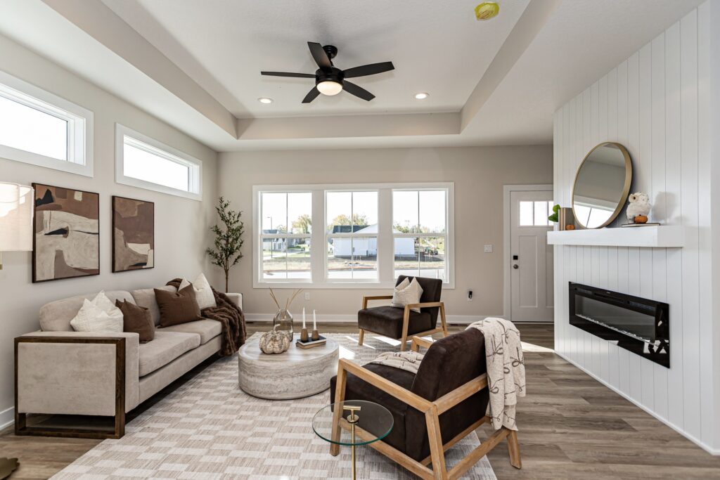 Bright living room with a ceiling fan and kitchen, highlighting Gladiator Homes available at 5825 Westfield Dr, Ames, IA.
