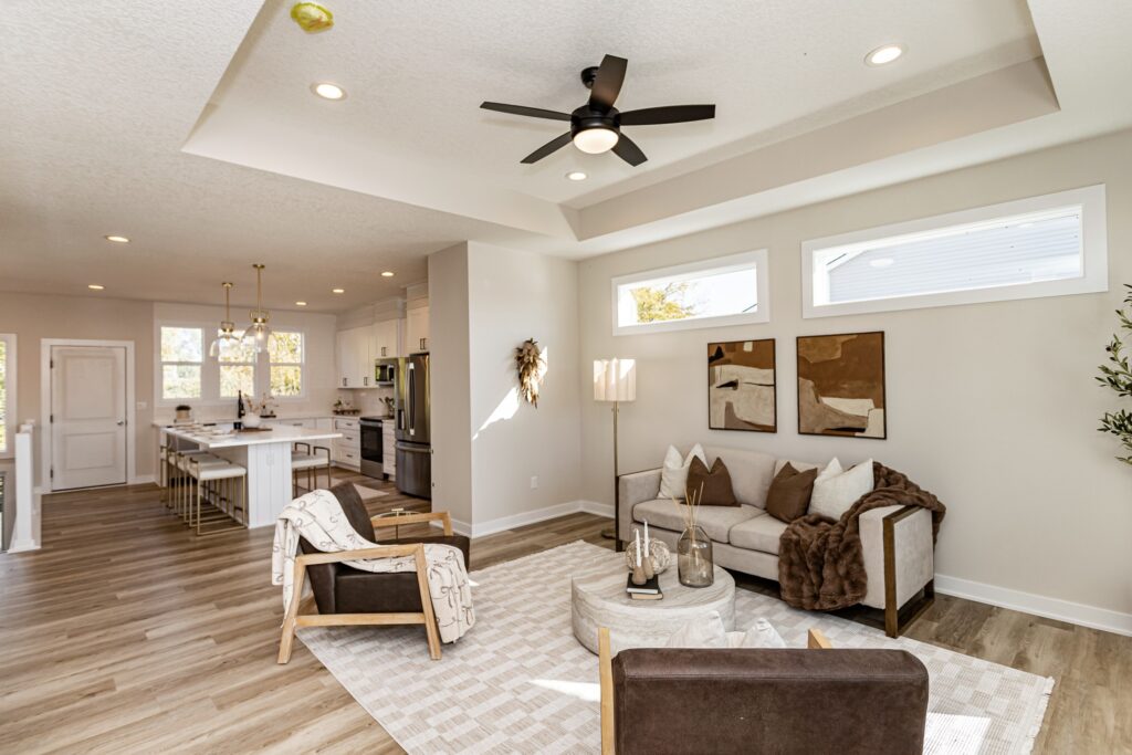 Bright living room with a ceiling fan and kitchen, highlighting Gladiator Homes available at 5825 Westfield Dr, Ames, IA.