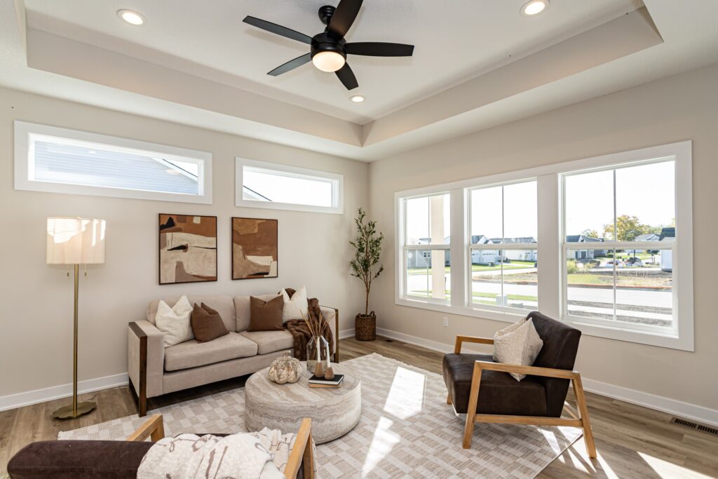 Bright living room with a ceiling fan and kitchen, highlighting Gladiator Homes available at 5825 Westfield Dr, Ames, IA.