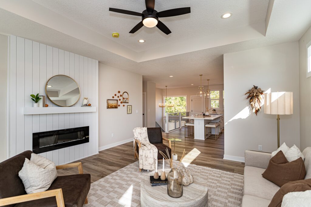 Bright living room with a ceiling fan and kitchen, highlighting Gladiator Homes available at 5825 Westfield Dr, Ames, IA.