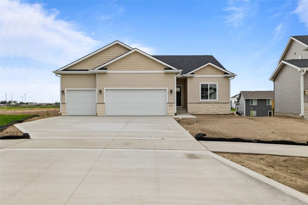 Front exterior of new construction ranch home with three-car garage, stone accents, and concrete driveway in Waukee, Iowa