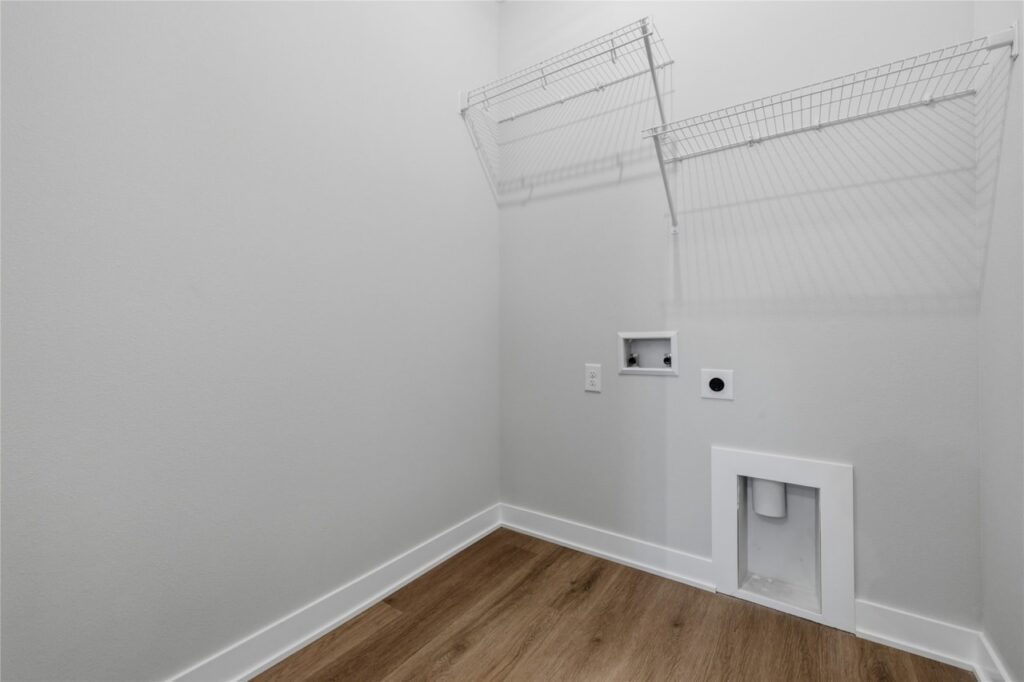 Laundry room with wire shelving, washer dryer hookups, pet door, and LVP flooring in Waukee Iowa new construction home