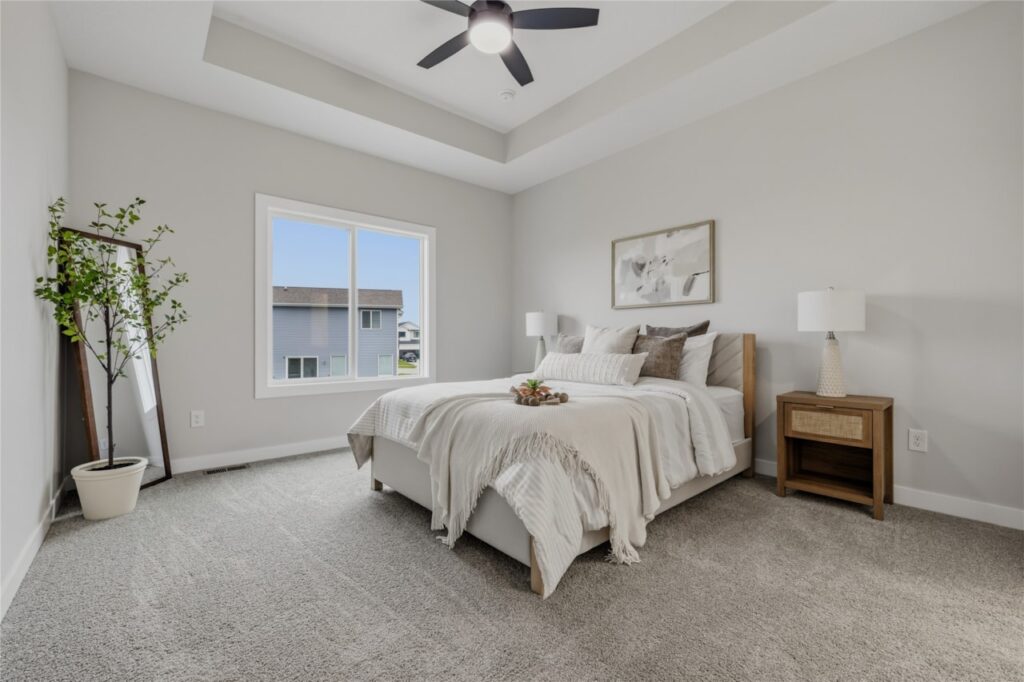 Spacious primary bedroom with tray ceiling, ceiling fan, and large window — your retreat at 325 NW Lavelle Ct, Waukee, IA. Built by Gladiator Homes.