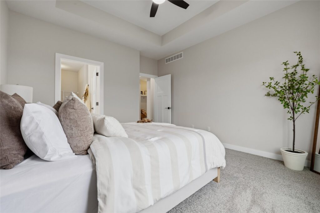 Primary bedroom with open doors to en-suite bathroom and walk-in closet in Waukee Iowa new construction home