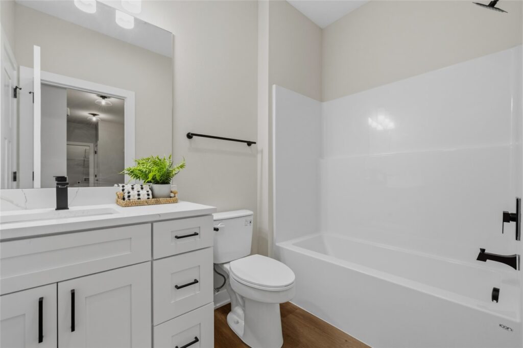 Secondary bathroom with white shaker vanity, quartz countertop, matte black faucet, and tub shower combo in Waukee Iowa new construction