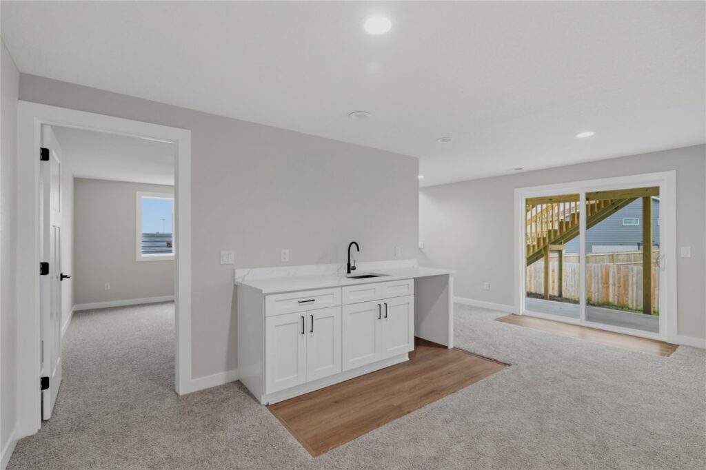 inished walkout basement with open rec room, white wet bar kitchenette, sliding door, and staircase in Waukee Iowa new construction