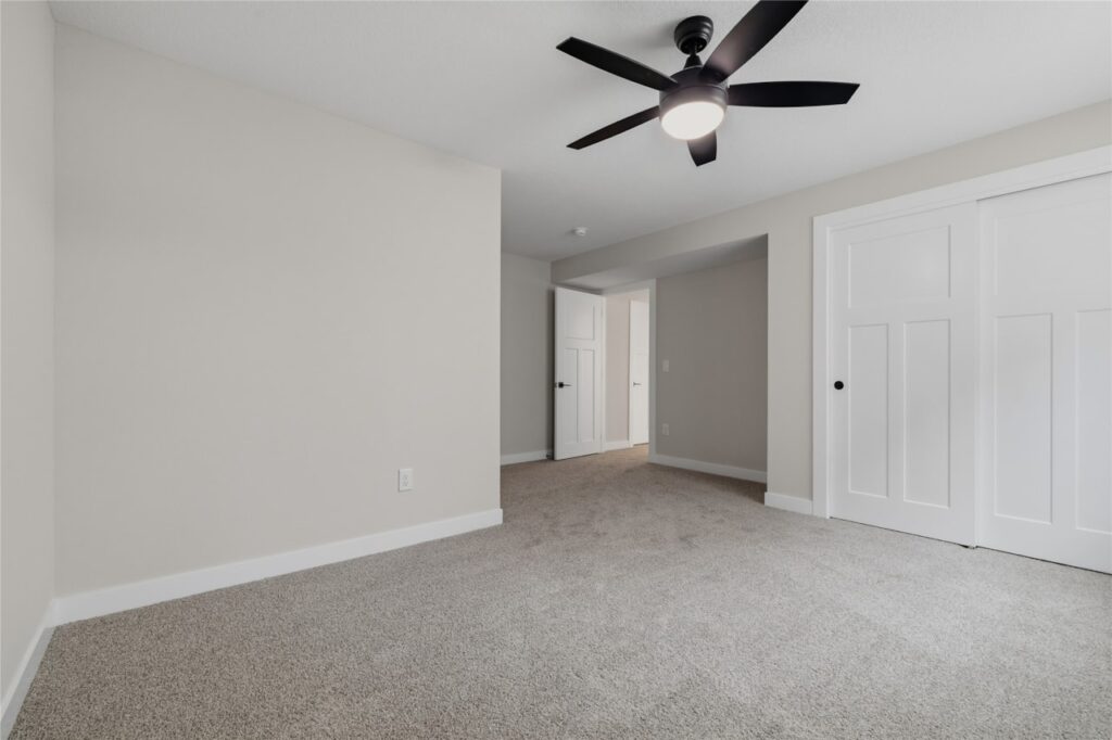 Full finished basement with large carpet rec room, wet bar, multiple bedroom doors, and staircase in Waukee Iowa new construction home
