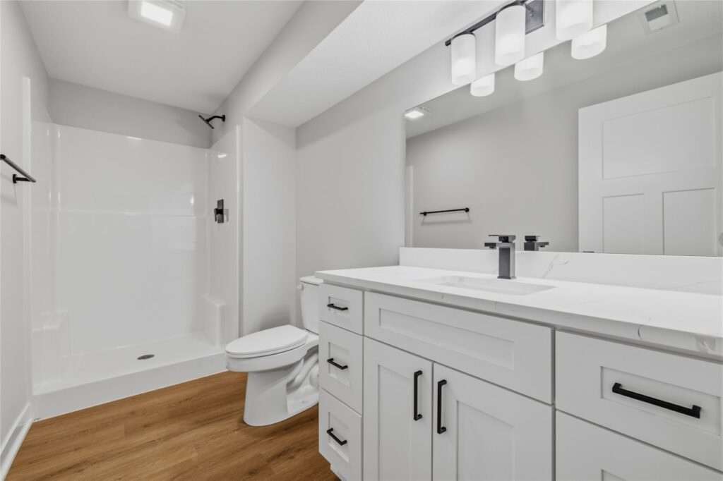 Lower level full bath with quartz vanity, matte black hardware, and walk-in shower — quality at every level at 325 NW Lavelle Ct, Waukee, IA. Built by Gladiator Homes.